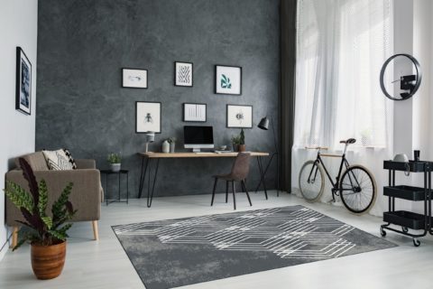 Tummanharmaa, modernisti valkoisella salmiakkikuvioitu Art Lyric-viskoosimatto modernin huoneen keskilattiamattona.