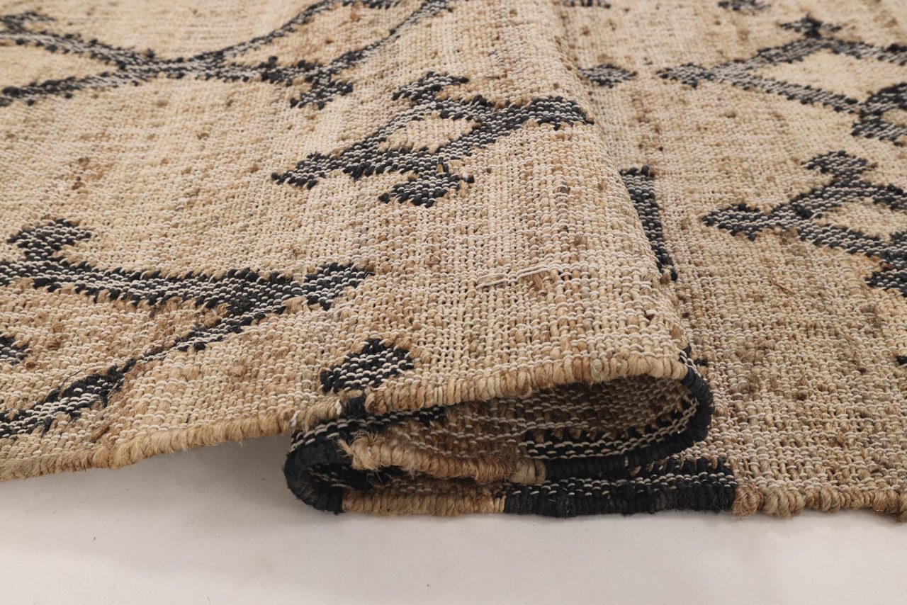 Mustilla kuvioilla kuvioitu Leyla-juuttimatto pohja ja reuna esiin taiteltuna. Myös maton kuviointi näkyy kuvassa.