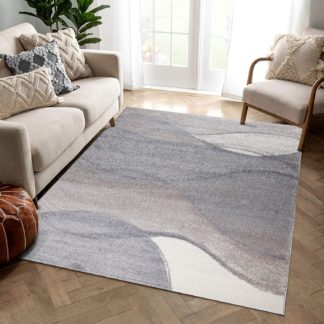 Tiheänukkainen, suorakaiteenmuotoinen beigen ja harmaan sävyinen Opal Mio-matto keskilattiamattona valoisan huoneen lattialla.