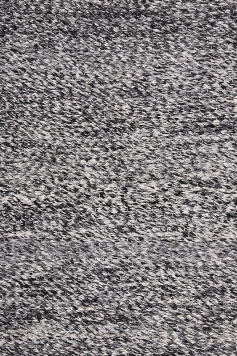 Mustavalkoinen, käsinkudottu Poseidon-matto pinta läheltä kuvattuna.
