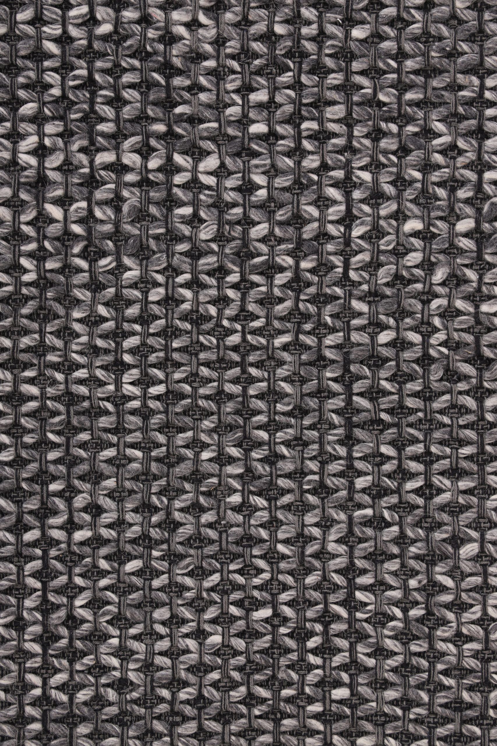 Käsinkudottu, tummanharmaa Saga-matto pinta läheltä kuvattuna.