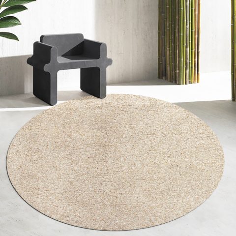 Kierrätetystä polyesteristä valmistettu, matalanukkainen, pyöreä beige Serene-matto valoisan huoneen lattialla.