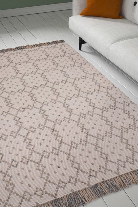Beige, kuviollinen ja hapsullinen Poseideon Elle-matto olohuoneen lattialla. Kierrätyspulloista valmistettu.
