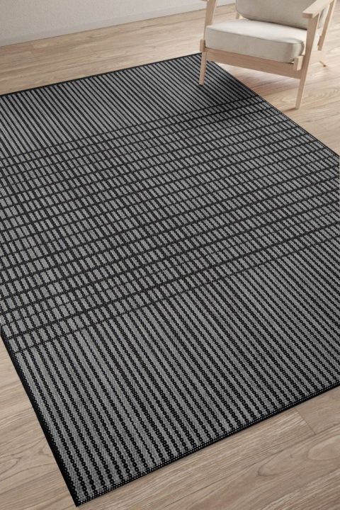 Sileäpintainen musta-harmaa Verdi Lia matto olohuoneen lattialla. Skandinaavinen raidoitus.